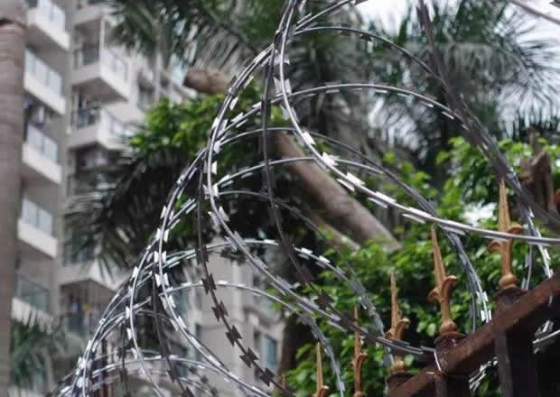 Hot dipped galvanized barbed tape coils atop picket fence panels